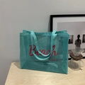 Grande borsa da spiaggia in rete verde menta con scritta Beach Vibes rossa su tavolo - Blu Lago Con Scritte Rosa