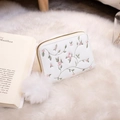 Monedero beige bordado con flores y pompón blanco sobre una alfombra suave - Blanco