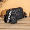 Sac bandoulière matelassé noir avec sangle large sur une surface en bois - Motif de Diamants Noir