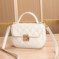 Elegant off-white quilted crossbody bag with golden clasp on a wooden surface - White