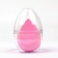 Roze druppelvormige make-up spons in een transparante eivormige stofvrije opbergdoos - Eierschaal Verpakking / Roze