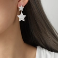Boucles d'oreilles double étoile en argent avec texture martelée portées par mannequin - Couleur Acier (Étoile Empilée)