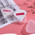 Set de borlas de maquillaje triangulares con cintas rojas y estuches sobre fondo rosa - Blanco