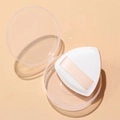 Detailansicht eines dreieckigen Make-up-Puffs in einer klaren runden Aufbewahrungsbox - Kartonverpackung / Weiß