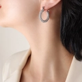 Elegante breite Creolen in Silber mit Zirkonia-Steinen, getragen von einem Modell - Silberne Ohrringe