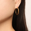 Close-up of golden twisted hoop earrings worn by a model showcasing metallic texture - Twisted Rope Style (F1418) / Gold