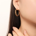 Close-up of stylish gold twisted hoop earrings worn by a model for a textured fashion look - Twisted Rope Style (F1419) / Gold