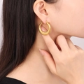 Orecchini a cerchio a U dorati massicci con finitura lucida su una modella donna - Stile F1198 / 32mm / Oro