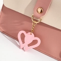 Detalle de bolso de cuero rosa granulado con colgante de corazón y cierre magnético dorado - Rosa
