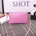 Pink croc-effect crossbody bag with gold-tone zipper charm and slim shoulder strap - Violet
