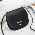 Minimalistische schwarze Satteltasche aus Leder mit goldenem Logo auf Weiß - Schwarz