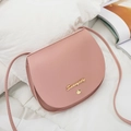 Schicke rosa Satteltasche aus PU-Leder mit goldenem Logo und Nieten auf weißem Bettzeug - Rosa