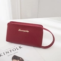 Chic burgundy lychee leather clutch bag with golden logo and circular wristlet strap - Burgundy