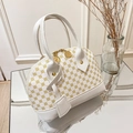 White shell handbag featuring yellow floral patterns on a mirrored tray display - White