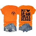 Detail view of bright orange T-shirt with MY HEART IS ON THAT STAGE back print - Orange (Black Font)