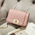 Pink quilted crossbody chain bag with golden metal lock on a grey sofa scene - Pink