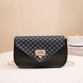 Chic black leather crossbody bag with patterned flap and gold chain strap on white fabric - Black