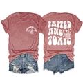 Flat lay of brick red T-shirt with TATTED AND TOXIC print and ripped denim shorts - Rose Gold (White Graphic)