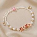 XOXO-Armband mit Perlen und rosa Herzverschluss auf beigem Satin-Hintergrund - XOXO Buchstaben Stil