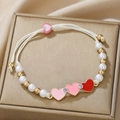 Close-up of pearl beaded bracelet with red heart charms on golden jewelry box - 3 Heart Pendants Style
