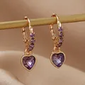 Détail de boucles d'oreilles cœur violet avec monture dorée et zircons scintillants - Violet