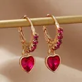 Vue détaillée de boucles d'oreilles cœur dorées avec pierres rouge rubis et cristaux - Rose rouge