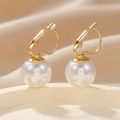 Primer plano de pendientes de perlas doradas sobre un fondo de seda suave - Blanco