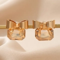 Vue macro de boucles d'oreilles nœud doré avec cristal ambré et finition polie chic - Doré