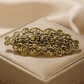 Detail van vintage gouden metalen haarklem met bloemenpatroon op een zijden ondergrond - Antiek Goud