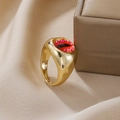 Detail eines Gold-Punk-Rings mit gelbem bösen Auge auf braunem Satinstoffhintergrund - Gold Rot Schlitzpupille