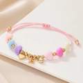 Detail of pink woven bracelet featuring macaron heart beads and gold letter E pendant - Letter E