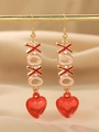 Détail de boucles d'oreilles XOXO dorées avec cœurs en émail rouge et strass - Style Coeur Lettre XOXO