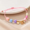 Detail of pink woven bracelet featuring colorful heart beads and gold M letter pendant - Letter M