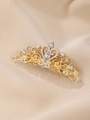 Dettaglio del fermaglio a corona dorata con cristalli bianchi su sfondo di seta champagne - Stile Corona di Strass