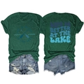 Flat lay of lake-themed green t-shirt with denim shorts showing front and back views - Vintage Green