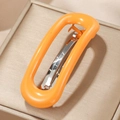 Pinza de pelo ovalada naranja en acetato sobre una elegante caja de joyería dorada - Naranja