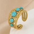 Macro detail of gold-plated twisted ring with five turquoise stone inlays on silk fabric - Sapphire