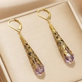 Detailed view of vintage gold hollow metal earrings with purple teardrop crystals - Purple