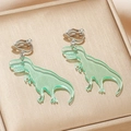 Close-up of cute light green acrylic dinosaur ear clips for girls on a gold texture box - T-Rex Style (EQ152) / Light Green T-Rex