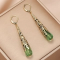 Macro detail of vintage teardrop earrings with green crystal and gold metal lever-back hooks - Green