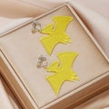 Detail of yellow acrylic bat clip-on earrings displayed on luxury silk and golden box - Yellow Pterosaur