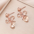 Detail van roségouden strik oorbellen met champagne zirkoon op een luxe sieradendoosje - Roségoud Strik Stijl (EQ252)