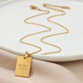 Collier élégant à pendentif carré doré avec gravure MORE LOVE sur fond de satin - Doré
