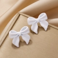 Elegant white flocked bow stud earrings on a gold display case with silk background - White with Bowknot