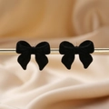 Elegant black flocked bow earrings on a silk background for a minimalist fashion style - Black Bow