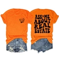 Flat lay of an orange cotton t-shirt and denim shorts with real estate agent slogans - Orange (Black Graphic)
