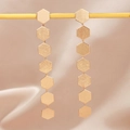 Minimalist matte gold hexagonal disc drop earrings displayed on elegant beige silk fabric - Golden Hexagon