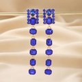 Elegant gold drop earrings with blue rhinestones displayed on champagne silk fabric - Blue Rectangular Dangle Earrings