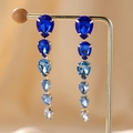Detailed view of teardrop crystal earrings with blue gradient stones on a golden display - Blue Waterdrop