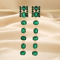 Macro view of long emerald green geometric earrings with gold dripping fringe on silk - Green Rectangular Dangle Earrings